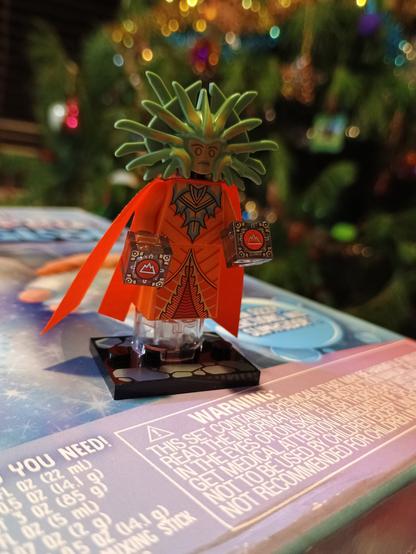 A Lego figurine of the Lady of Pain, from the Planescape D&D setting.  The figurine is orange with an expressionless green face and seems to float above the ground.