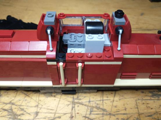 Closeup of the BlueBrixx V100 freight train loco with a chinese no-name, 2.4 GHz receiver built into the driver's cabin. A black corner plate can be seen which should be dark red to match the color of the train.