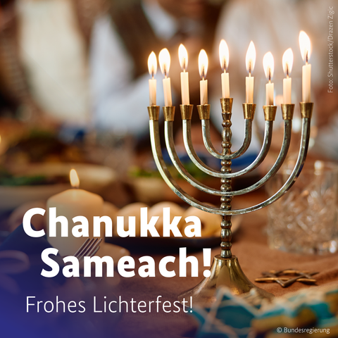 Eine Grafik mit der Aufschrift "Chanukka Sameach!" und einem Bild im unteren Bereich, das einen festlich gedeckten Tisch mit einer angezündeten Chanukkia (neunarmiger Chanukka-Leuchter) zeigt. Im Text darunter steht: "Frohes Lichterfest."
