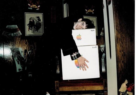 Kay on Christmas morning hugging two large boxes with the old colorful Apple logo on them