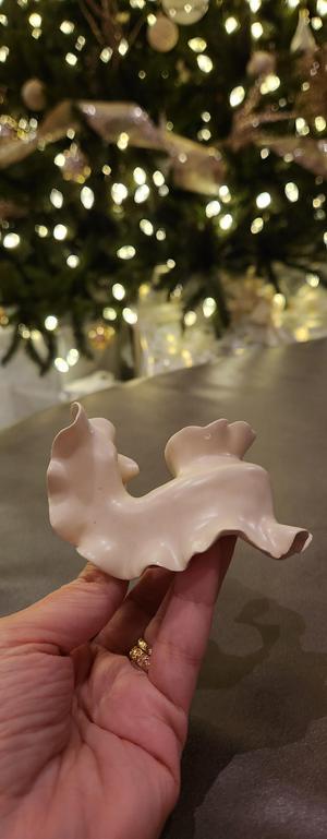 Biomorphic ceramic sculpture with clear glaze representing a nudibranch with Christmas lights in the background.