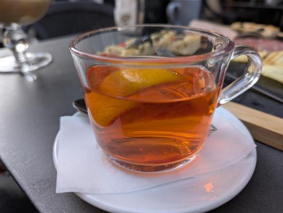 A glass mug with an orange drink with a slice of blood orange: a hot mandarin orange punch.