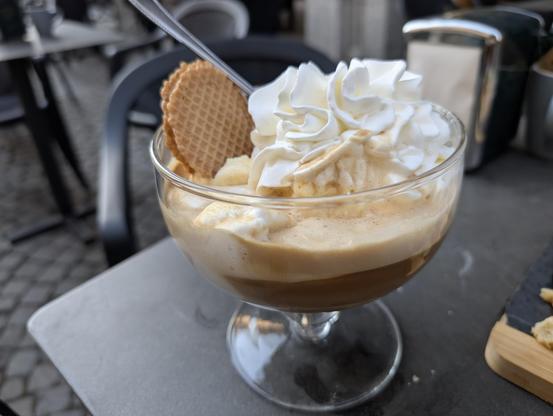 A caffè affogato: a wide glass cup with ice cream that's been "drowned" (affogato in Italian) in coffee, with whipped cream and a wafer biscuit.