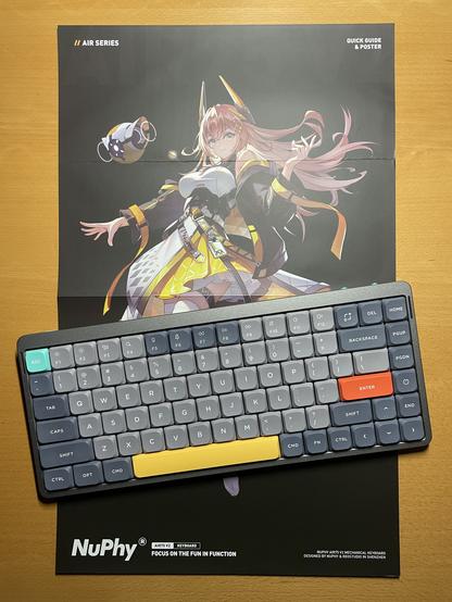 75% keyboard on a table. Spacebar in yellow, escape key in green and return key in red. ANSI layout with low profile switches. Keyboard lays on a anime poster from nuphy.
