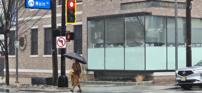A monk walking on alms in the rain on Main St.