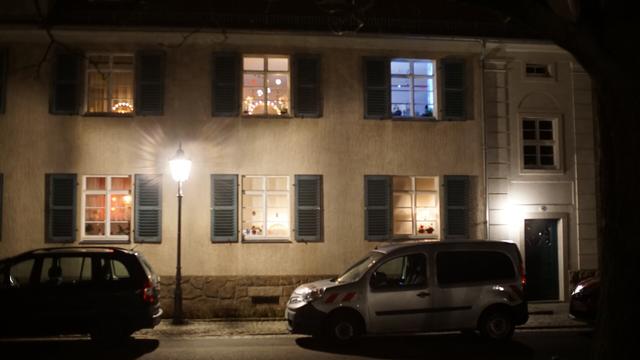 Haus mit Weihnachtsdeko in den Fenstern - davor wieder eine Straßenlaterne