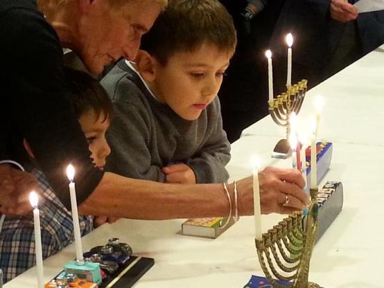 Children watch intently as Hanukah candles are lit on the first night