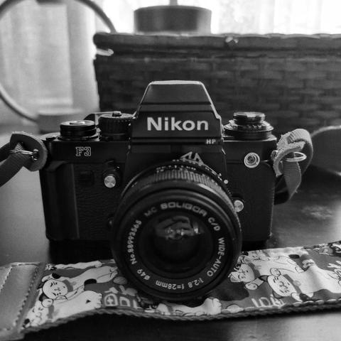 Black and white image of a Nikon F3HP with a Soligor 28mm f/2.8 lens attached.