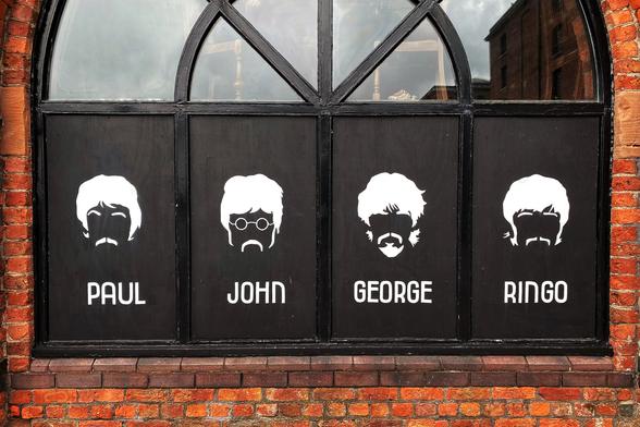 Colour photo of a black and white litho type mural of The Beatles with their names and faces in white on a black background