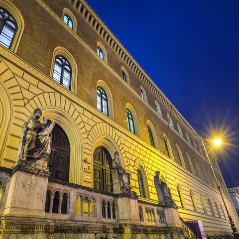 Das beleuchtete Eingangsportal der Bayerischen Staatsbibliothek bei Nacht.