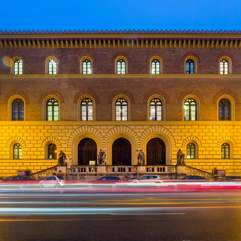 Das beleuchtete Eingangsportal der Bayerischen Staatsbibliothek bei Nacht.