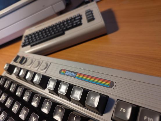A 8Bitdo retro mechanical keyboard in the style of an original C64 bread bin case. A TheC64 mini in the background.