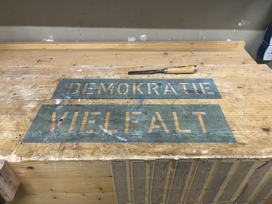 Zwei gelasterte Plexi Stencils mit "Demokratie" und "Vielfalt". Schutzfolie abpulen kostet extra.
