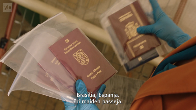 Kuvakaappaus Yle Areenasta mainitusta ohjelmasta, jossa sinihanskaiset kädet pitävät minigrip-pusseihin suljettuja eri maiden passeja. Kuvassa näkyy selvästi Suomen passi.