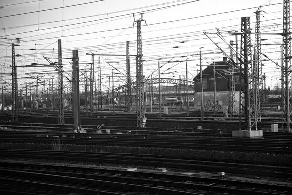 A forest of railway masts and a multitude of tracks. A signal box and a railway bridge in the background.