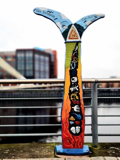 An ornate millenium milepost on a cycle network which has been painted in bright colours to help pick out its details.
