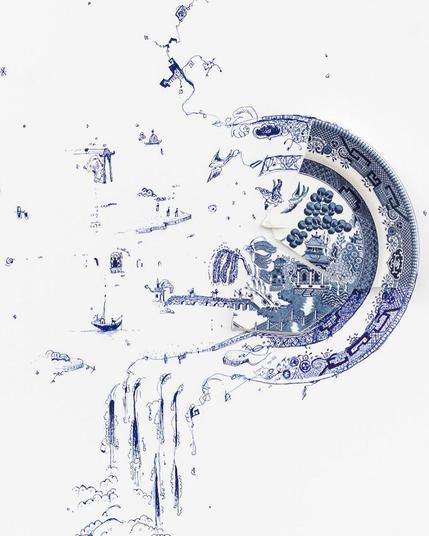 Artwork by Rob Strati from the 'Fragmented' series. The piece features a shattered blue-and-white decorative plate incorporated into an imaginative pen drawing. The fragments extend into a flowing scene with waterfalls, bridges, and small architectural details, blending the plate’s original design into a whimsical new narrative.