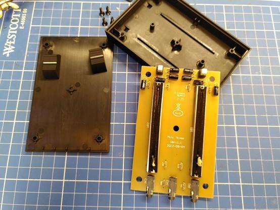 Disassembled device: screws are hidden below rubber feet, slider knobs are held in place with a piece of masking tape (friction fit)
