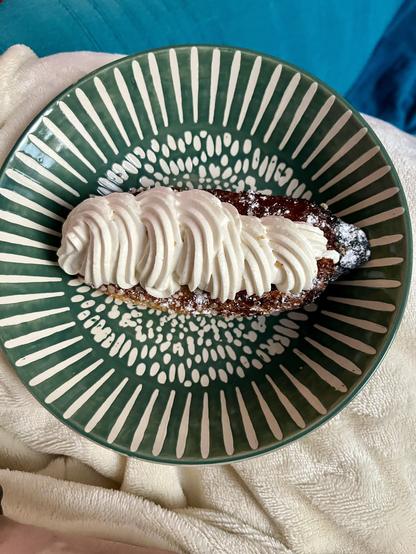 Photo d'un éclair à la chantilly dans une assiette creuse verte et blanche