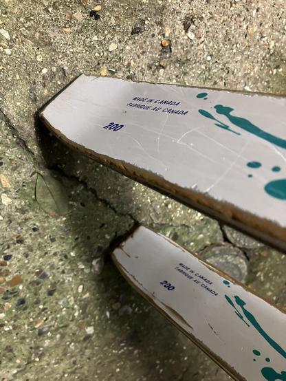 Tails of a pair of Kahru Nordic skis standing on a concrete surface