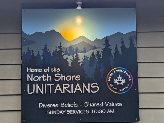5' square coloured sign with sun, mountains and forest. Wording - "Home of The North Shore Unitarians.  Diverse Beliefs - Shared Values.  Sunday services 10:30 am