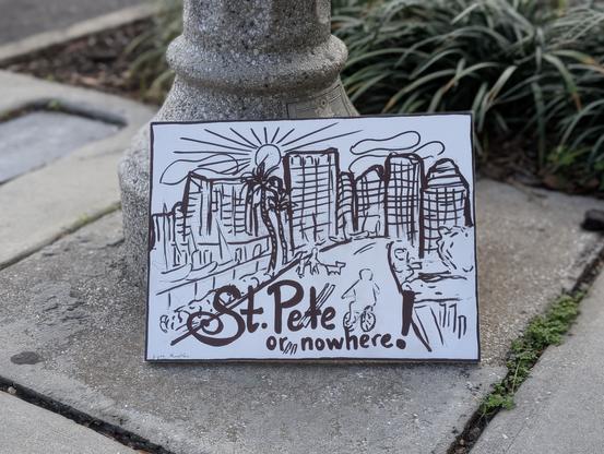Photo of hand-drawn ink art showing a stylized Florida city. There's a road with people biking and walking pets, boats docked in a marina, palm trees, a city skyline, and a sun in a partly cloudy sky. At the bottom is written "St. Pete or nowhere!"