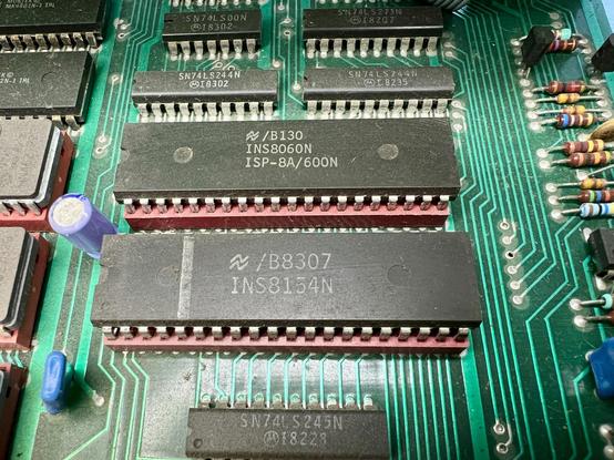 Two 40-pin DIP chips, the SC/MP processor and 128kx8 RAM I/O chip, in fetching red sockets.