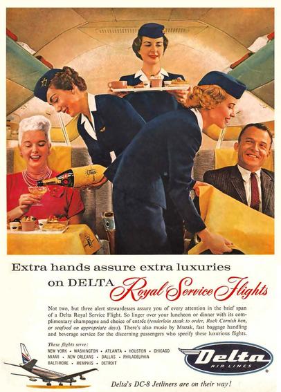 Three flight attendants serve passengers on a Delta Air Lines Flight. One is pouring champagne from a bottle to a well-dressed older woman. Two others serve food, to the man across the aisle.