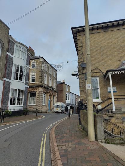 a van parked on a pavement, forcing 3 people to walk/roll on the road