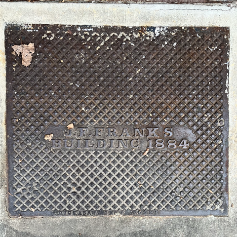 Square hatch cover marked “J F FRANKS BUILDING 1884”