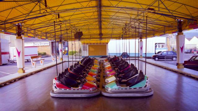 A dodgems rink, with two lines of cars neatly parked.