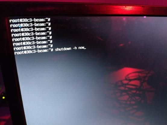 Photo of a root shell showing the prepared command "shutdown -h now", before it is executed