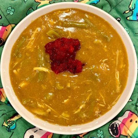 A bowl of curry with turkey, green beans, and cranberry sauce.