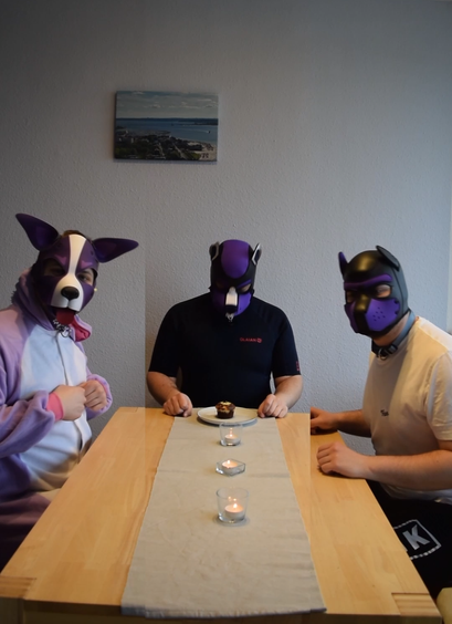Three human puppies around a table, one eating a muffin