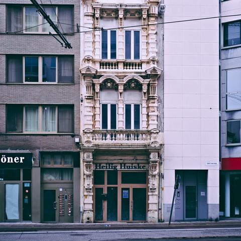 A narrow tall building in Antwerp, white and in a classical architectural style. The text above the main facade states "Heilig Huiske".