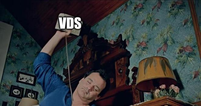 Screenshot aus dem Film "Und täglich grüßt das Murmeltier" - ein Mann ist schlaftrunken kurz davor, einen Wecker auf den Boden zu schmeissen um ihn auszuschalten. Über dem Wecker steht die Abkürzung "VDS" geschrieben