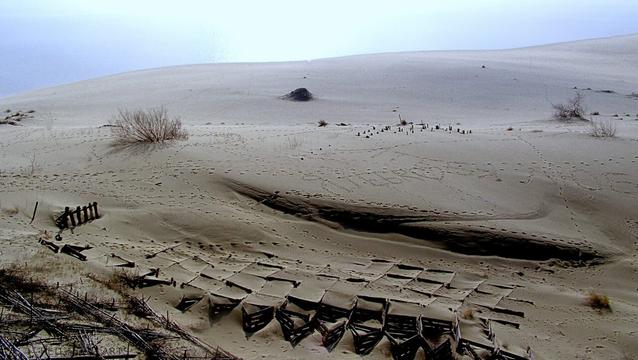 Dünenlanschaft an der Ostsee mit Fußspuren und unterschiedlichen Holzkonstruktionen gegen das Wandern des Sandes.
Dune landscape on the Baltic Sea with footprints and various wooden constructions to prevent the sand from shifting.
Kopų kraštovaizdis prie Baltijos jūros su pėdsakais ir įvairiomis medinėmis konstrukcijomis, neleidžiančiomis smėliui judėti.