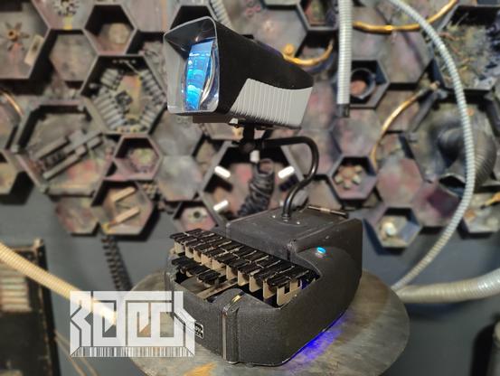 A sculpture by RETECH of a small device playing video on a screen. Device is built from an amalgam of old tech.