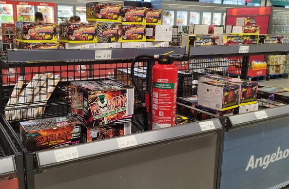 Tisch in einem Supermarkt auf dem Böller angeboten werden und mittendrin ein Feuerlöscher
