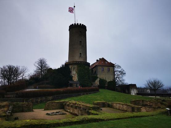 Bild der Burg und Festung #Sparrenberg, Wahrzeichen der Stadt #Bielefeld. In der Mitte sieht man den Turm mit der Turmfahne und rechts daneben das Restaurantgebäude. Im Vordergrund erkennt man dir Grundmauern der Ruine des Zeughauses.