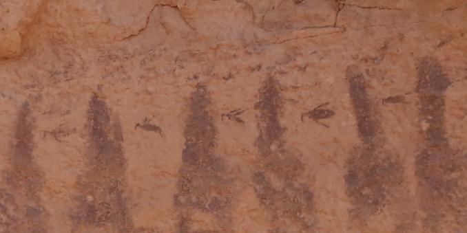 A pictograph on red sandstone with dark stripes representing canyons and between each stripe is a bird