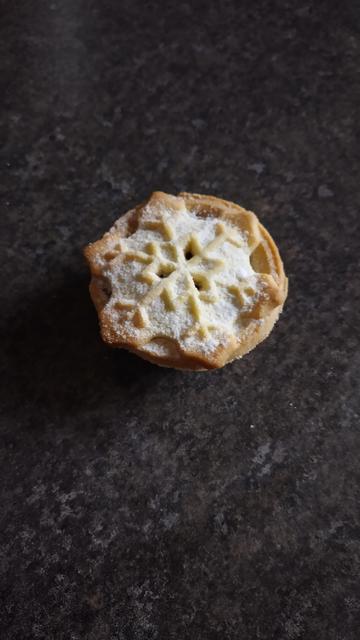 A single delicious mince pie, with a snow flake patterned top.