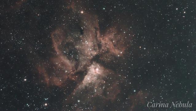 The Eta Carina Nebula complex, red-orange, with many dark dust lanes and swirling filaments of glowing gas.