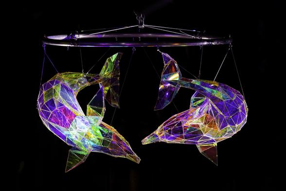 Two dolphins made from colored glass facing each other.