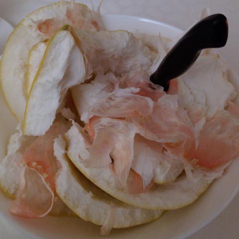 Schale und Reste einer Pomelo in einer Schüssel, in die ein Messer hineingestochen ist