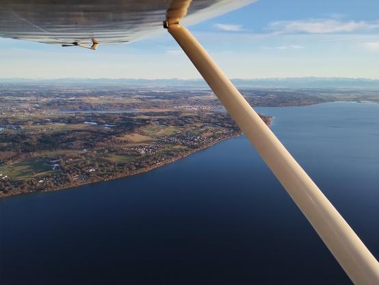 View from the plane, below left wing. Great weather. Above Ammersee (Lake Ammer) and the Alps in the background.