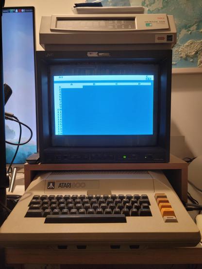 A wide shot of my Atari 800 with the JVC monitor displaying VisiCalc. An OKI dot-matrix printer sits atop the monitor.