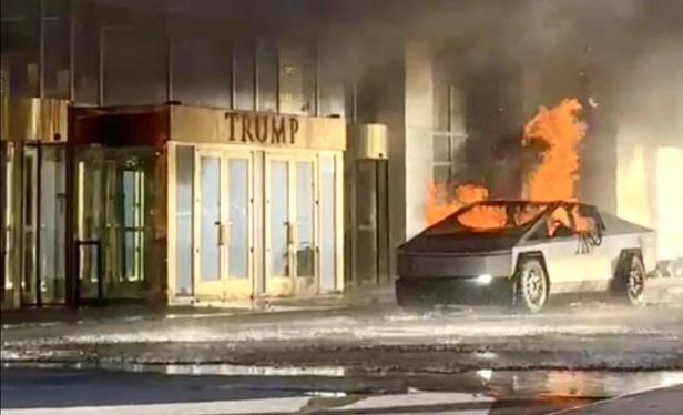 A Cybertruck burning outside of a hotel lobby. "TRUMP" is written in large gold letters on top of the main doors