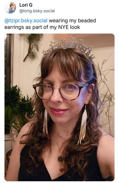 Lori G @lorig.bsky.social posted: @tzipr.bsky.social wearing my beaded earrings as part of my NYE look

Selfie of Lori G wearing white, silver, and gold beaded fringe earrings and a "Happy new year" silver headband with stars