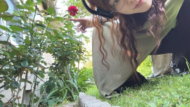 SoYoon in the garden, pointing at a red flower, wearing headphones, being magical.